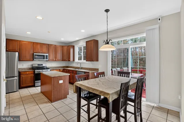 a kitchen with stainless steel appliances granite countertop a stove top oven a sink a dining table and chairs