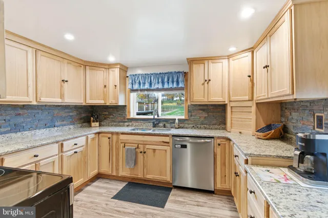 a kitchen with granite countertop a sink cabinets stainless steel appliances and a window