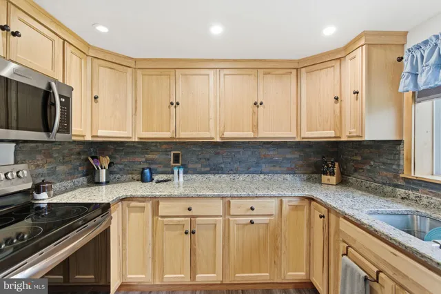 a kitchen with stainless steel appliances granite countertop a sink a stove and cabinets