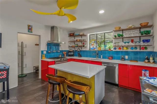 a room with stainless steel appliances kitchen island granite countertop a table chairs and a refrigerator