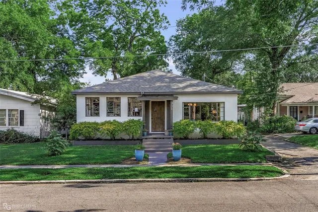 a front view of a house with a yard and potted plants