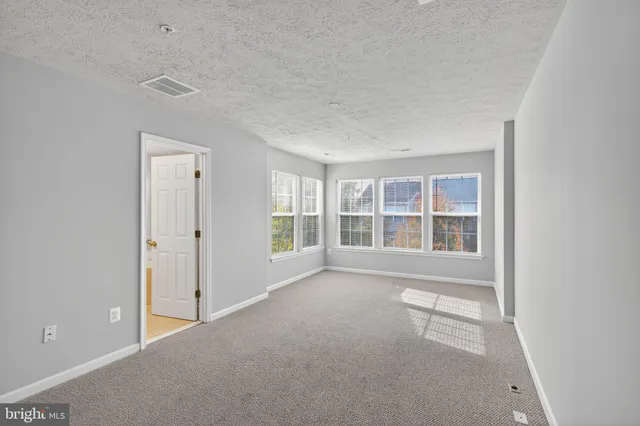 a view of an empty room with wooden floor and stairs