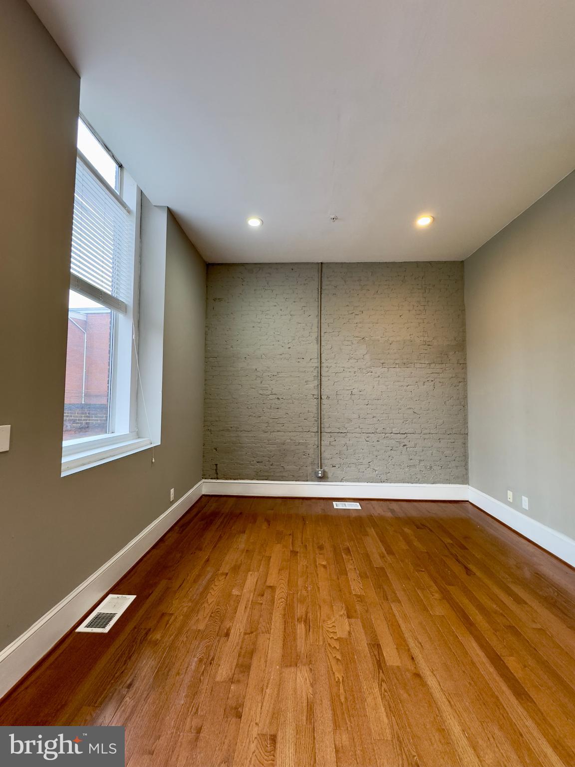 7 West Mulberry Street, Unit 4 Baltimore, MD 21201 - Photo 6 of 19 a view of an empty room with wooden floor and a window