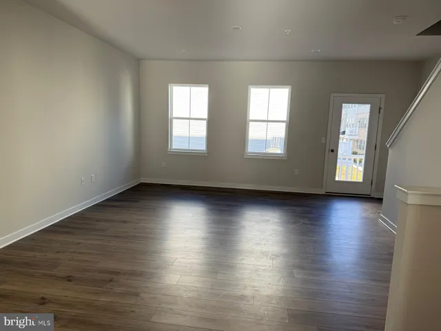an empty room with wooden floor and windows with curtains