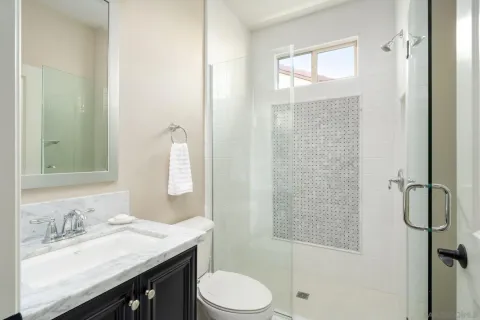 a bathroom with a granite countertop sink toilet a mirror and shower