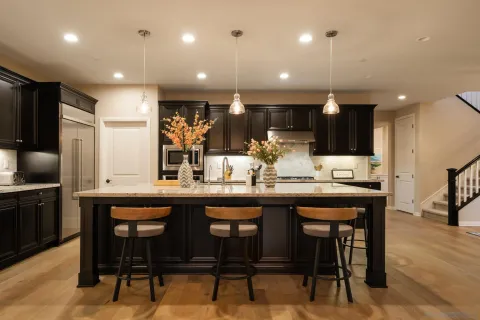 a kitchen with stainless steel appliances kitchen island granite countertop a table chairs sink and microwave