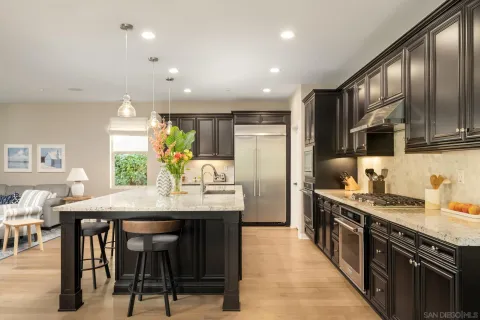 a kitchen with stainless steel appliances granite countertop a stove top oven a sink dishwasher a dining table and chairs with wooden floor