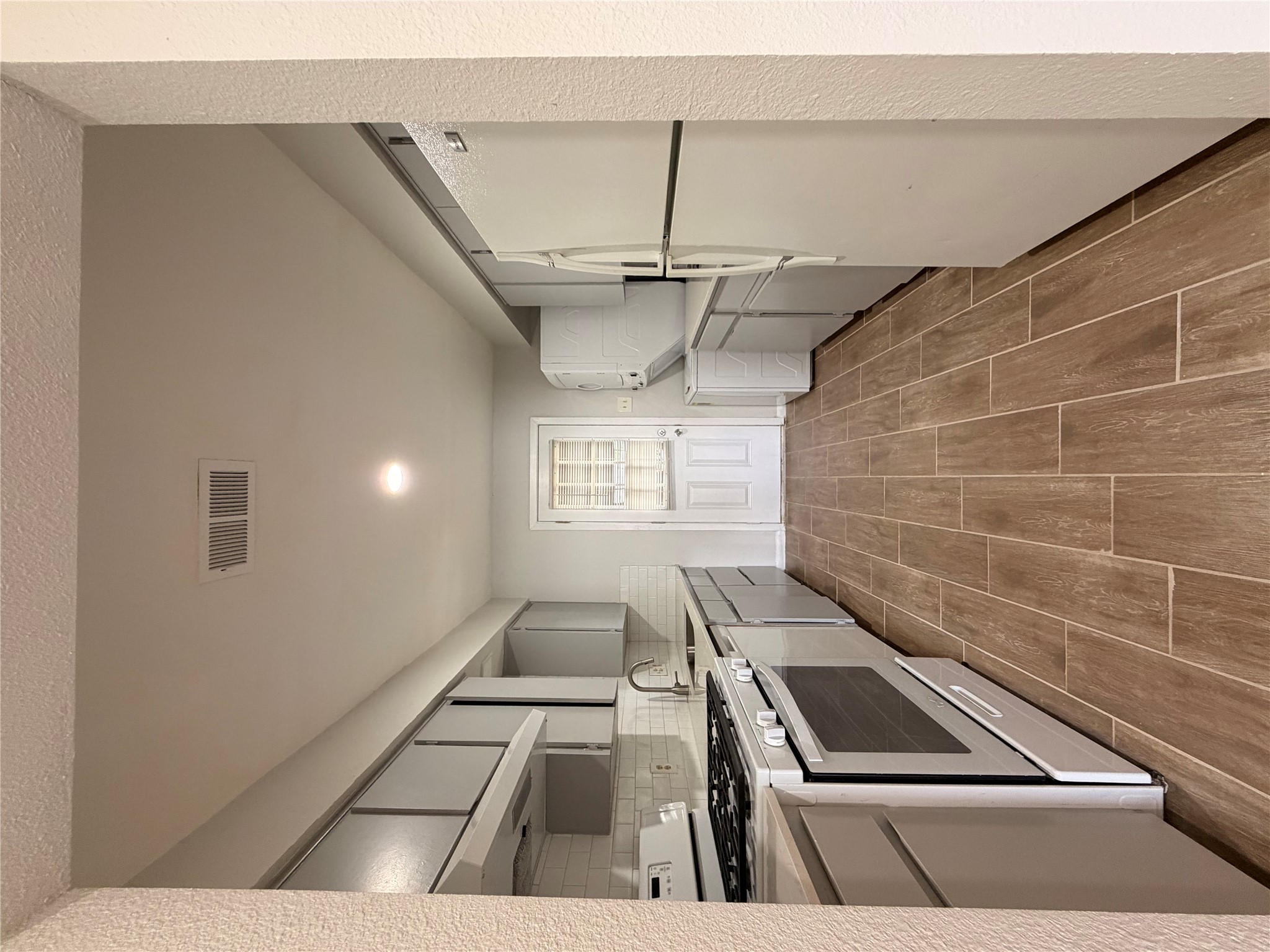 604 Gaylor Street, Unit B Austin, TX 78752 - Photo 3 of 5 A galley kitchen with wood-look tile flooring leads to an exterior door.