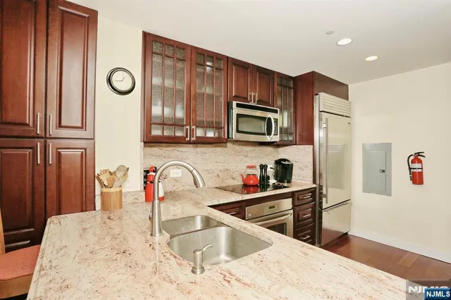 a kitchen with stainless steel appliances granite countertop a sink refrigerator stove and microwave