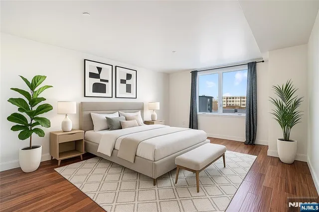 a bedroom with a large bed a potted plant and attached bathroom