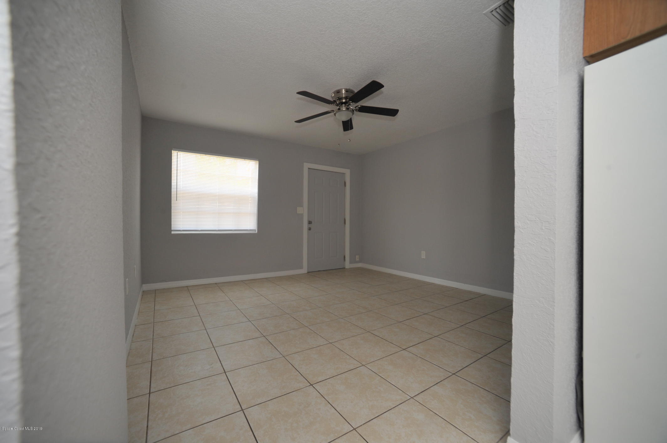1049 Mitchell Street Cocoa, FL 32922 - Photo 11 of 12 an empty room with windows and ceiling fan