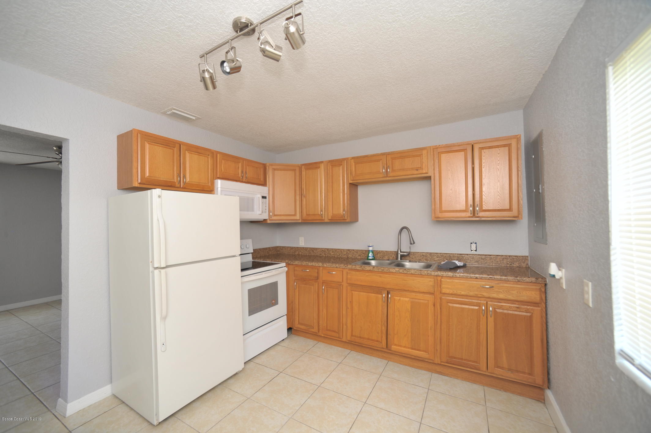 1049 Mitchell Street Cocoa, FL 32922 - Photo 4 of 12 a kitchen with a sink refrigerator and window