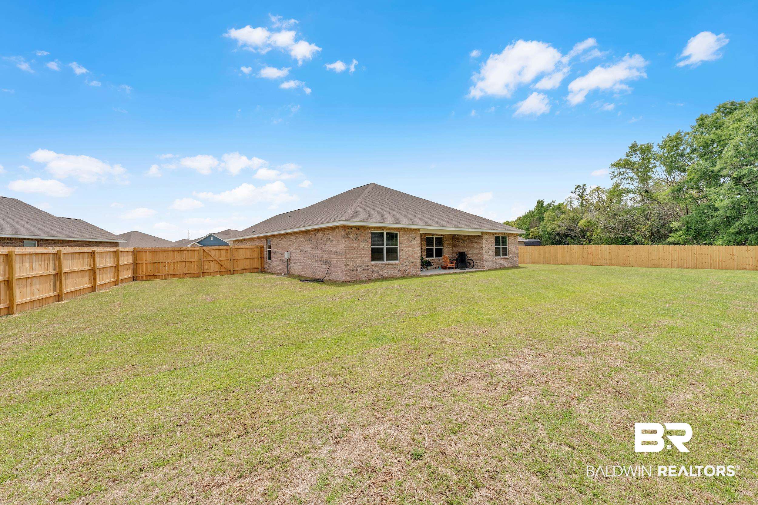 24460 Ringneck Loop Elberta, AL 36530 - Photo 10 of 46 Rear view of property with brick siding, a fenced backyard, and a lawn