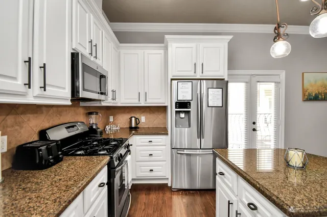 a kitchen with granite countertop a sink a stove and refrigerator