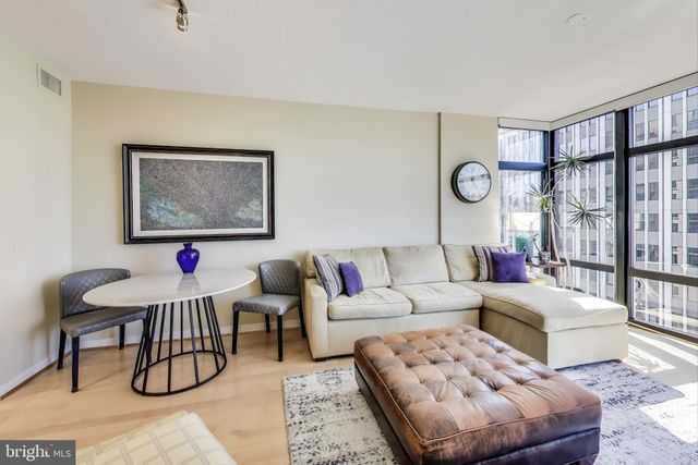 a living room with furniture a rug and wall paintings