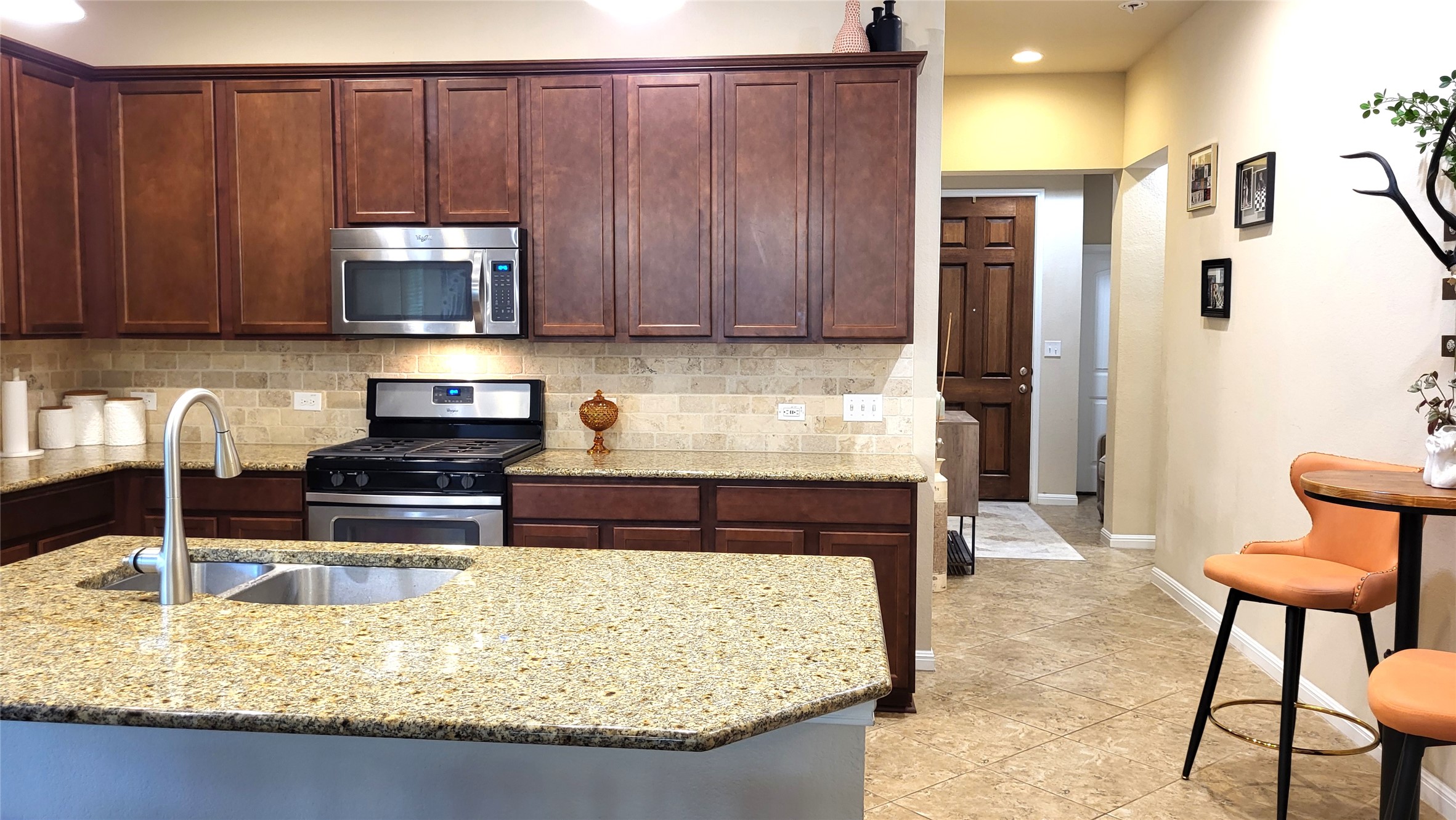 413 Anacua Loop, Unit 8 Manchaca, TX 78652 - Photo 9 of 23 Rich wood cabinetry and granite countertops anchor this kitchen alongside a central preparation island.