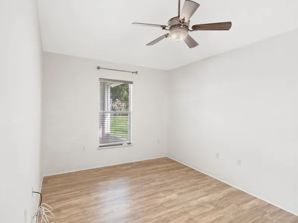 an empty room with a window and a fan