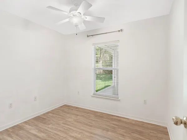 an empty room with a window and a ceiling fan