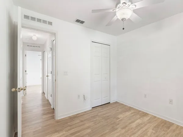 an empty room with wooden floor and ceiling fan