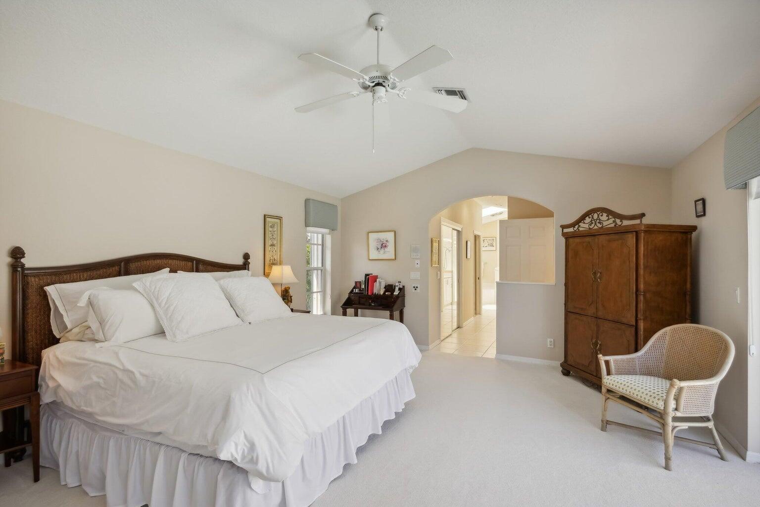 16481 Riverwind Drive Jupiter, FL 33477 - Photo 21 of 49 a bedroom with a bed a chandelier and a chair