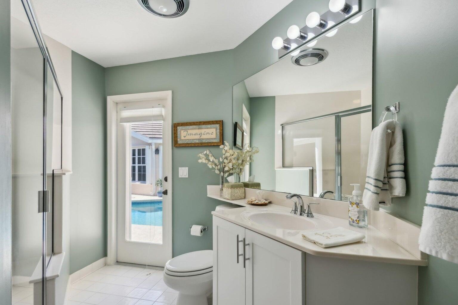 16481 Riverwind Drive Jupiter, FL 33477 - Photo 36 of 49 a bathroom with a granite countertop sink a toilet and a mirror