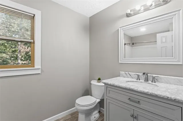 a bathroom with a granite countertop toilet a sink and mirror