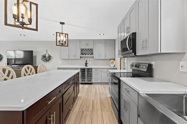 a kitchen with stainless steel appliances a sink dishwasher a stove top oven a refrigerator with wooden cabinets and floor