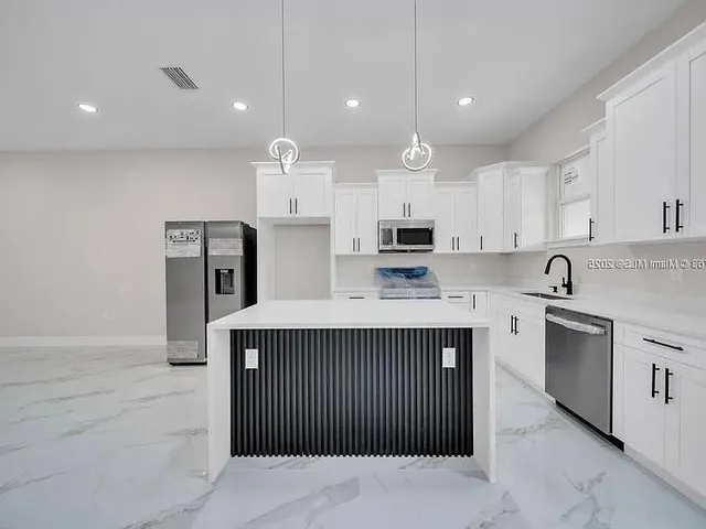 a kitchen with stainless steel appliances kitchen island granite countertop a refrigerator and a sink