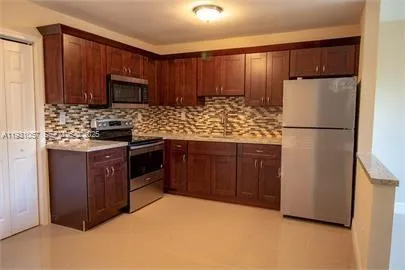 a kitchen with kitchen island wooden cabinets stainless steel appliances and a refrigerator