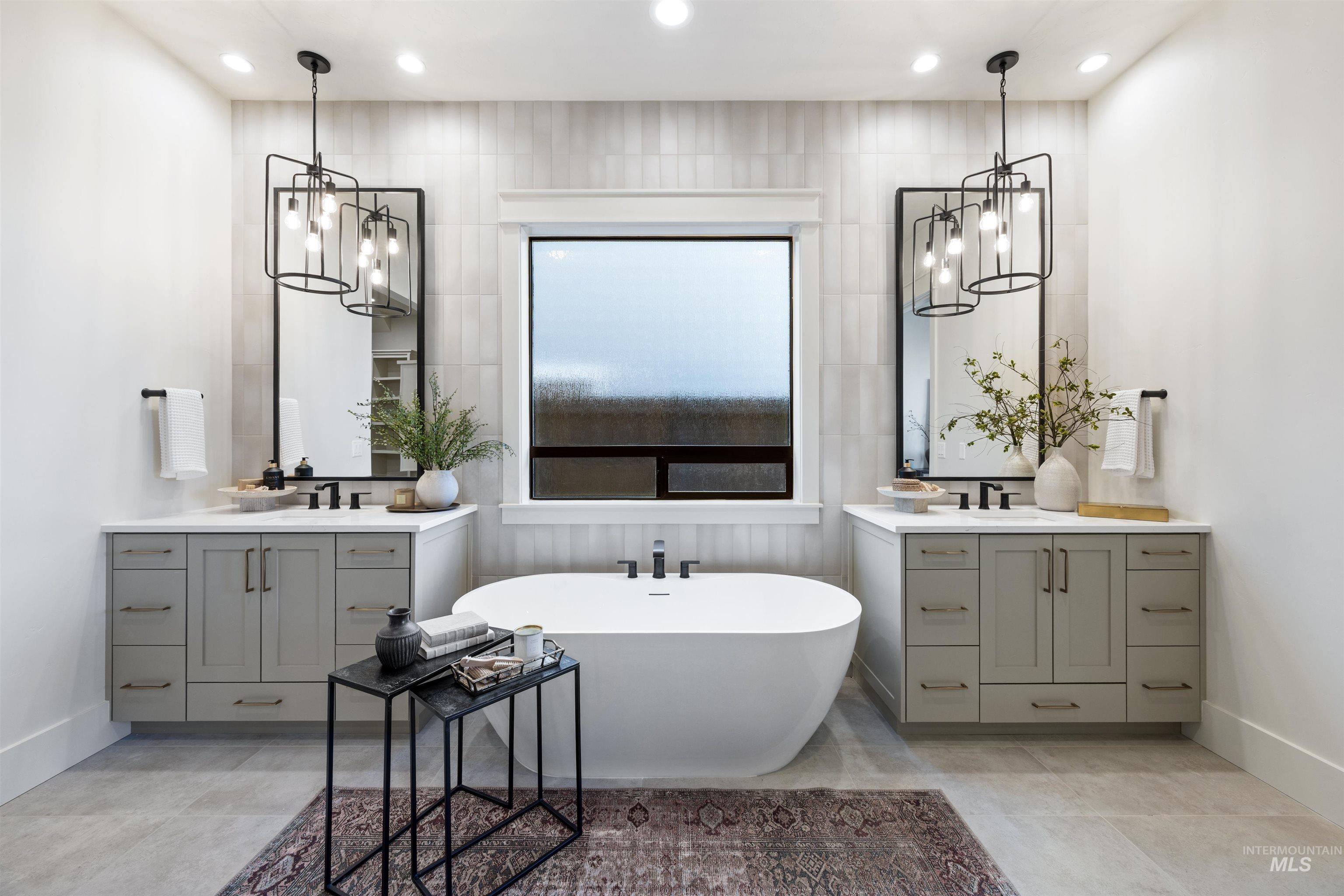 5847 South Pinpoint Way Meridian, ID 83642 - Photo 31 of 44 Bathroom with suspended lighting, two vanities, a soaking tub, and tile walls