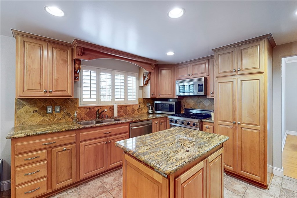 a kitchen with stainless steel appliances granite countertop a sink stove refrigerator and window