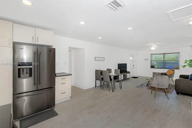 a kitchen with stainless steel appliances refrigerator dining table and chairs