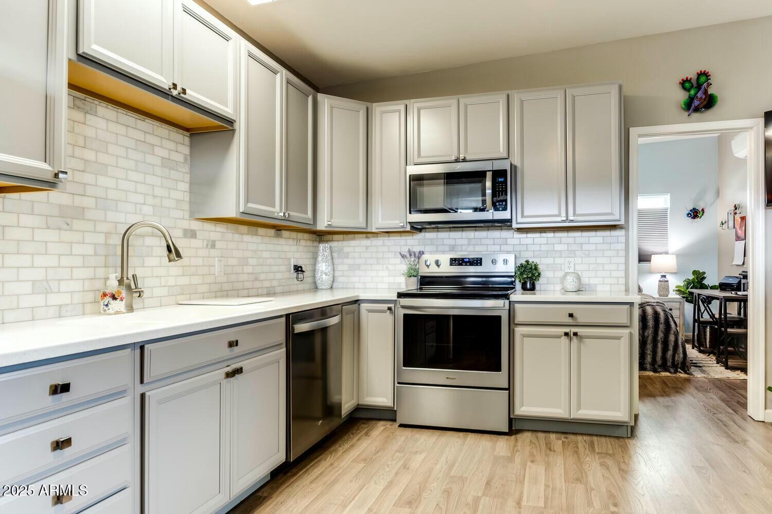 17200 West Bell Road, Unit 903 Surprise, AZ 85374 - Photo 8 of 21 a kitchen with cabinets stainless steel appliances a sink and wooden floor