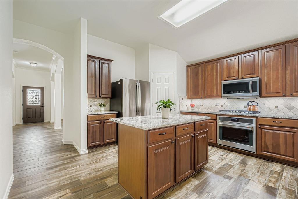 12407 Hawk Creek Drive Frisco, TX 75033 - Photo 11 of 33 a kitchen with kitchen island granite countertop stainless steel appliances and wooden cabinets