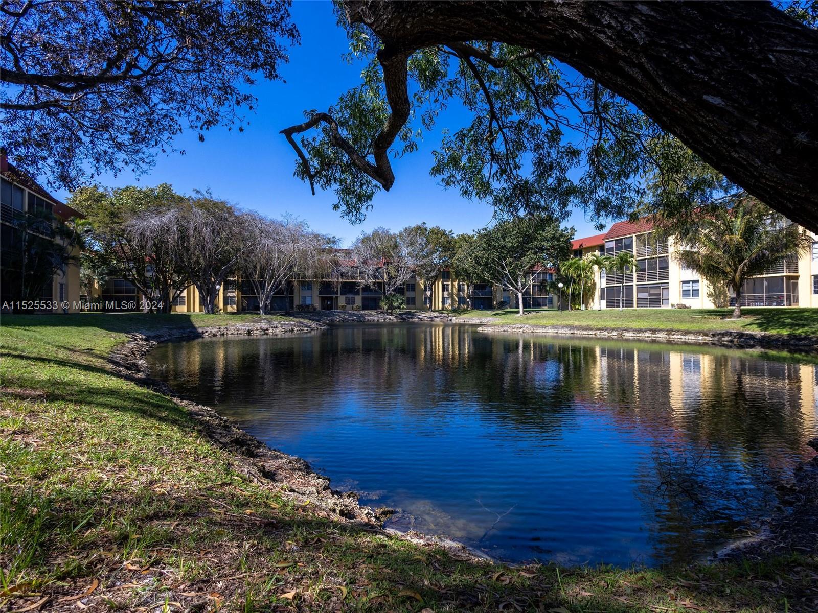 3285 Foxcroft Road, Unit E206 Miramar, FL 33025 - Photo 2 of 35 a view of a lake with a house in the background