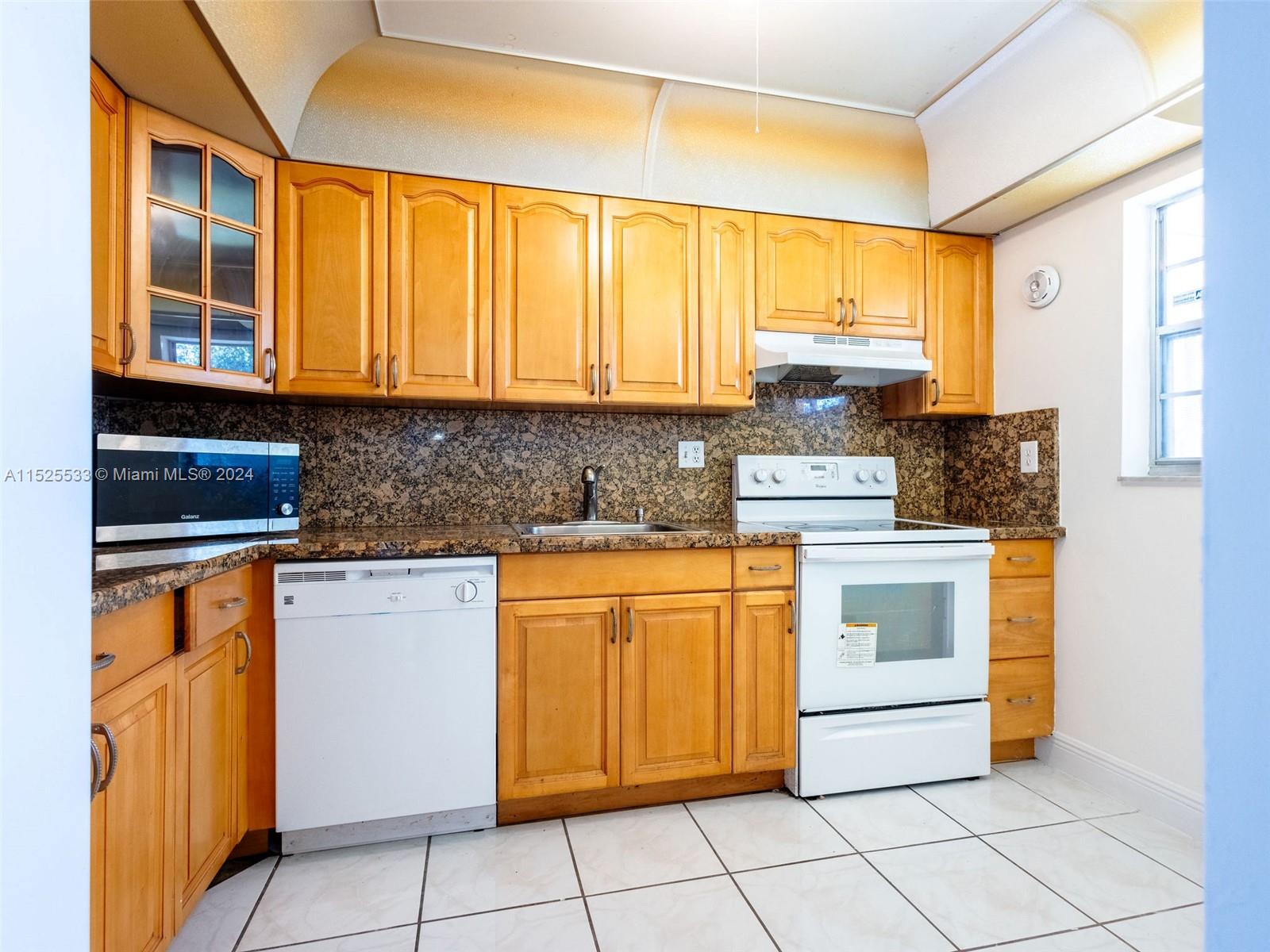 3285 Foxcroft Road, Unit E206 Miramar, FL 33025 - Photo 8 of 35 a kitchen with stainless steel appliances granite countertop a stove a sink and a microwave