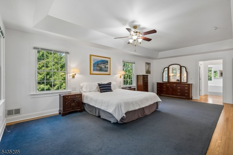 12 Oak Hill Road Bernards, NJ 07920 - Photo 13 of 33 a spacious bedroom with a large bed and a chandelier