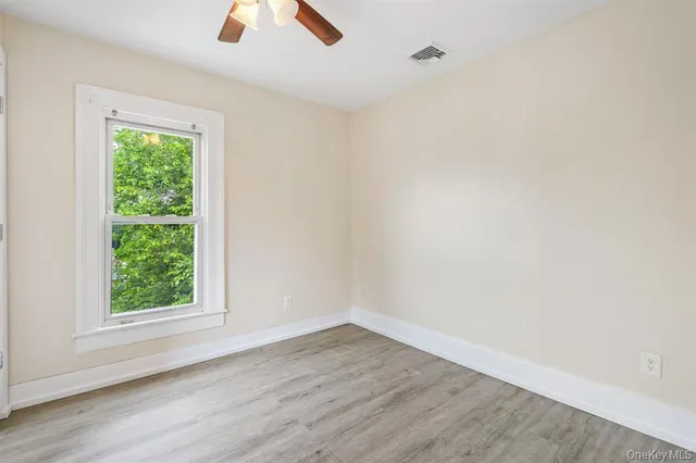 an empty room with a window and a ceiling fan
