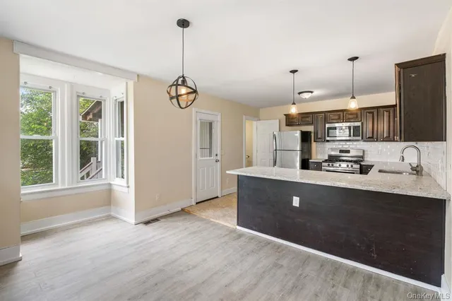 a kitchen with kitchen island granite countertop a sink cabinets and stainless steel appliances