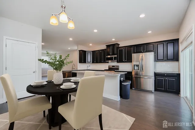 a kitchen with a refrigerator a stove a sink a dining table and chairs