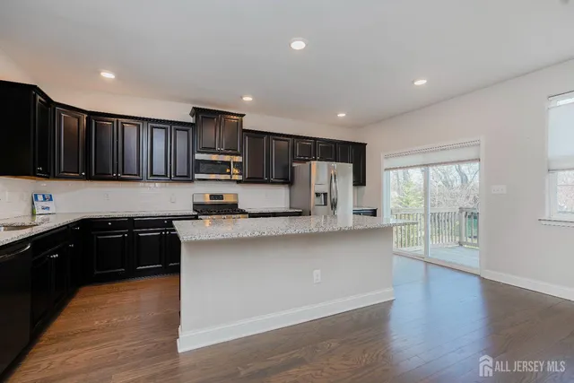 a kitchen with stainless steel appliances granite countertop a refrigerator a stove top oven a sink and dishwasher with wooden floor