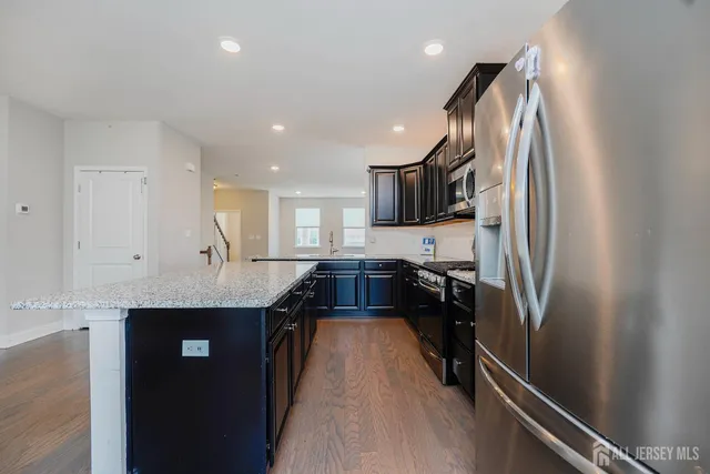 a kitchen with kitchen island granite countertop a sink appliances and cabinets