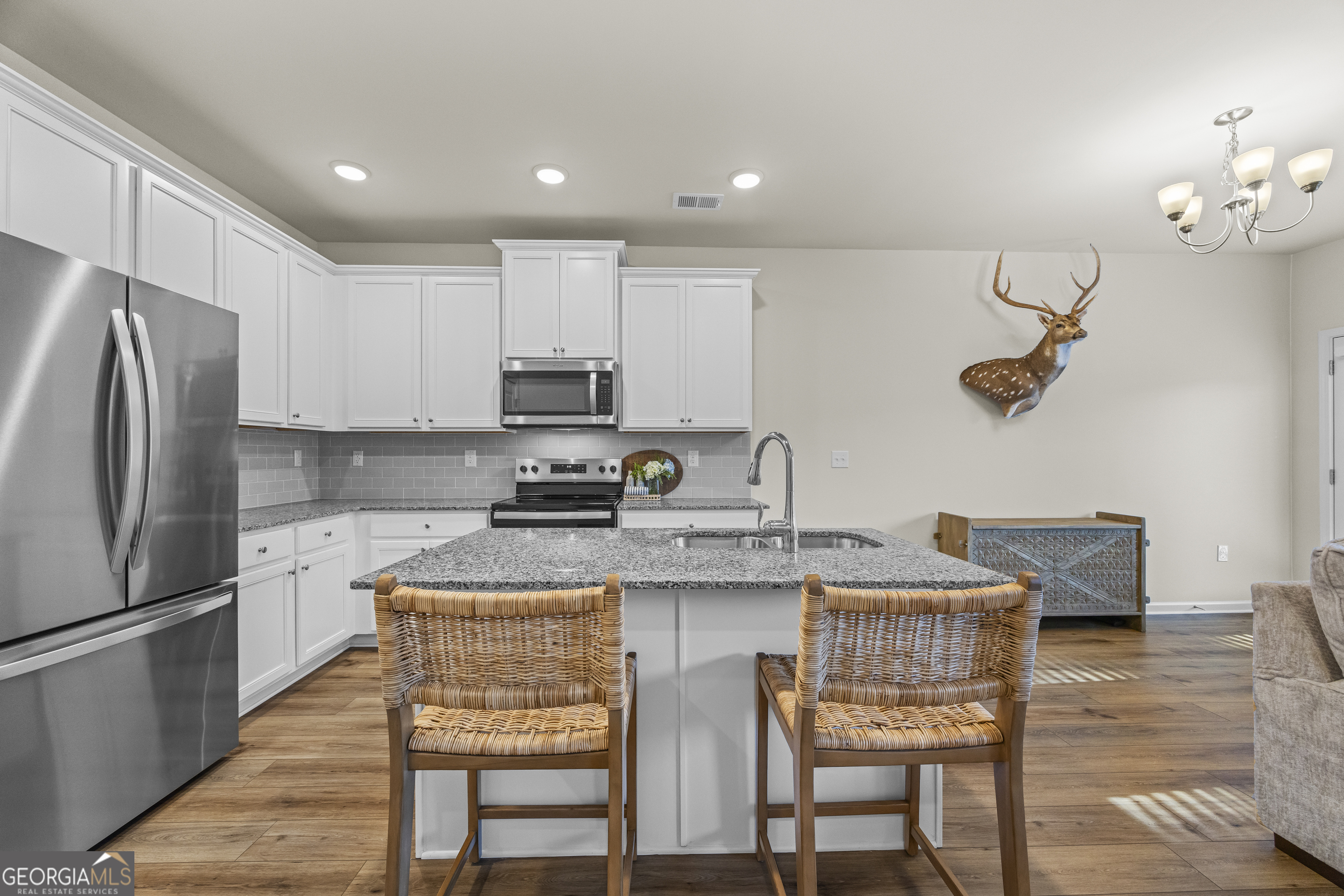 550 Buxton Road Hoschton, GA 30548 - Photo 11 of 57 a kitchen with kitchen island granite countertop a table chairs microwave and cabinets