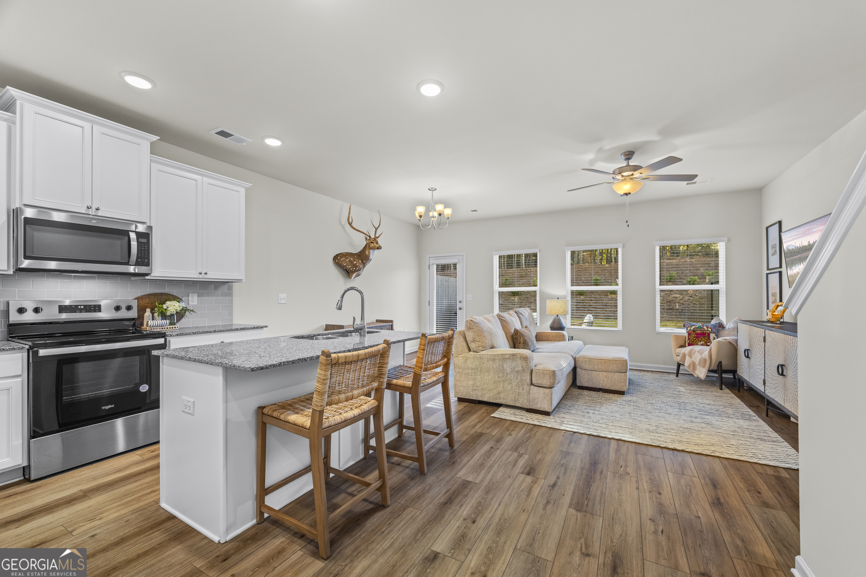 550 Buxton Road Hoschton, GA 30548 - Photo 9 of 57 a kitchen with stainless steel appliances granite countertop a stove top oven a sink dishwasher a dining table and chairs with wooden floor