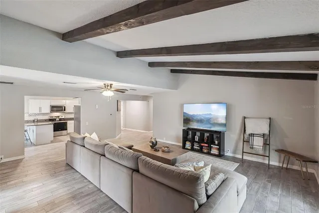 a kitchen with stainless steel appliances granite countertop a sink a microwave oven a refrigerator with white cabinets and wooden floor