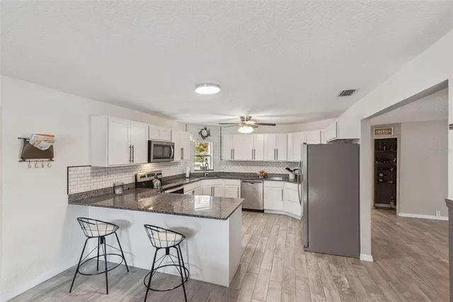 a kitchen with granite countertop a sink stainless steel appliances and white cabinets