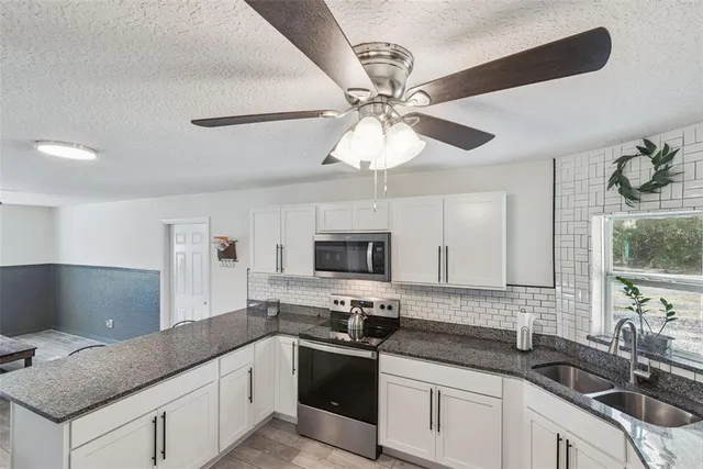 a kitchen with stainless steel appliances granite countertop a refrigerator a sink dishwasher a stove and a dining table with wooden floor