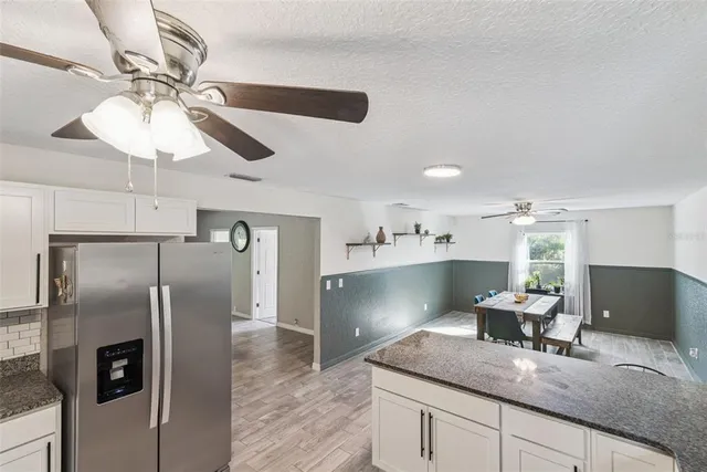 a large kitchen with stainless steel appliances kitchen island granite countertop a refrigerator and stove