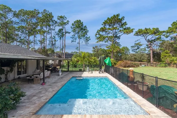 a view of a swimming pool with a patio and a yard