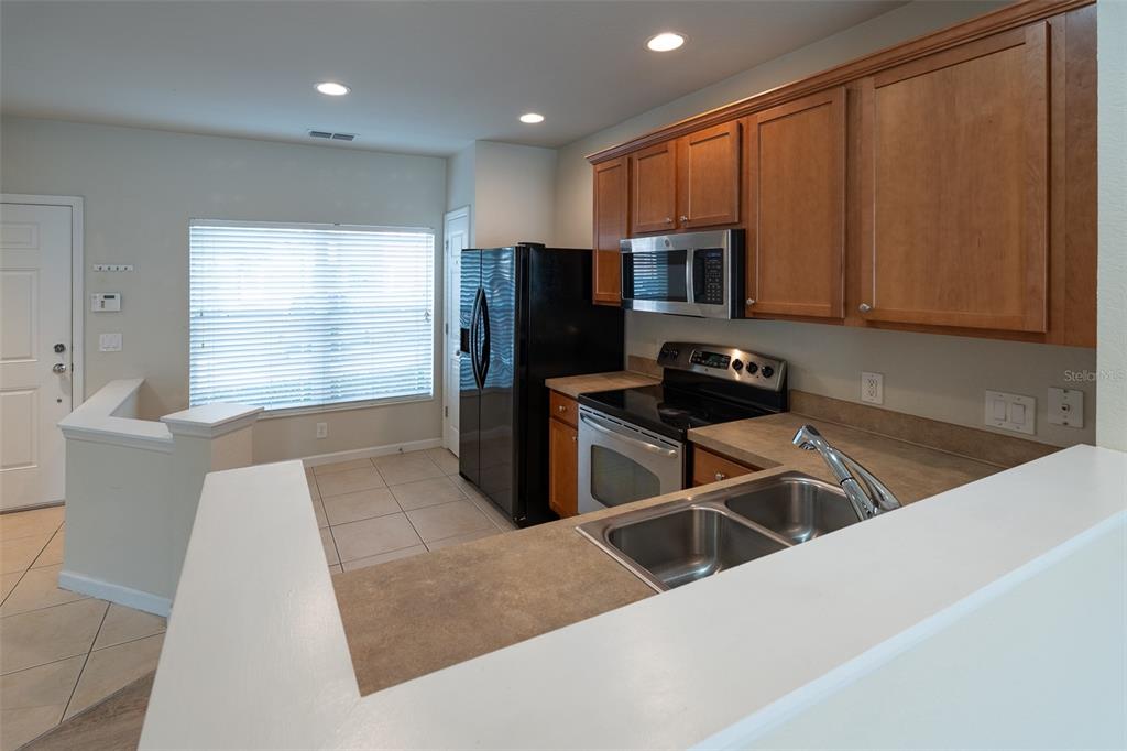4900 Southwest 45th Street Ocala, FL 34474 - Photo 13 of 44 a kitchen with stainless steel appliances wooden cabinets a stove a sink and a microwave